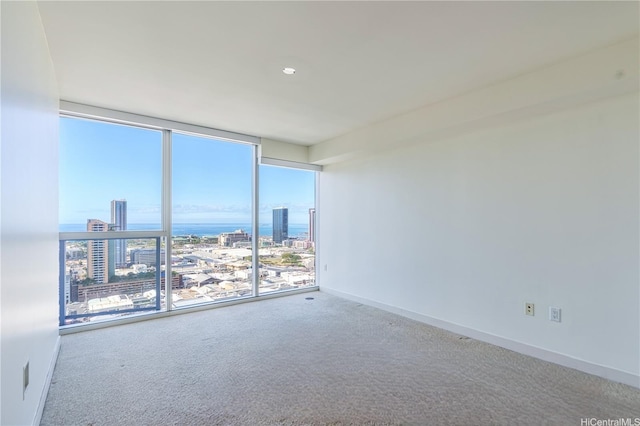 unfurnished room with expansive windows, a view of city, carpet flooring, and a water view
