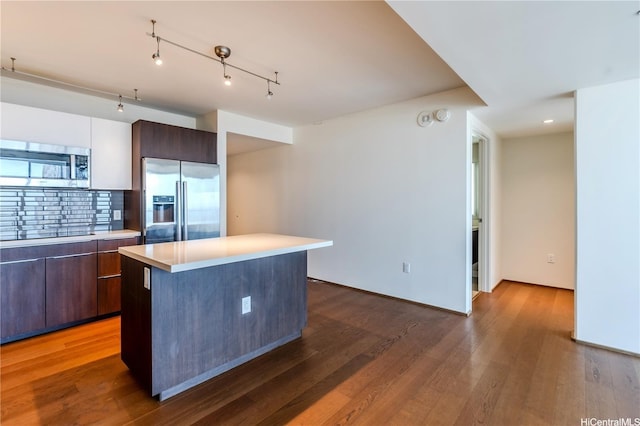 kitchen with stainless steel appliances, light countertops, modern cabinets, dark wood-type flooring, and a center island