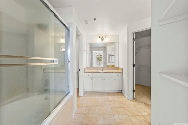 full bathroom featuring a spacious closet, a tile shower, tile patterned flooring, vanity, and visible vents