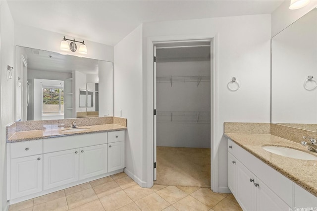 bathroom with two vanities, a spacious closet, tile patterned flooring, and a sink