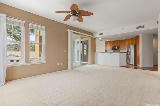 unfurnished living room featuring visible vents, ceiling fan, and plenty of natural light