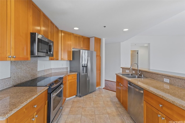 kitchen with recessed lighting, a sink, light stone counters, and stainless steel appliances