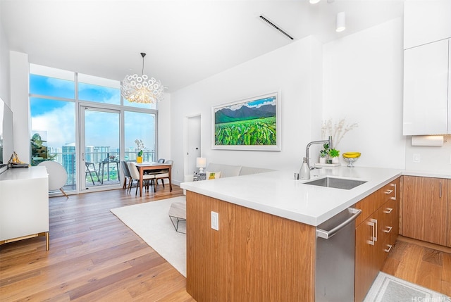 kitchen with a sink, light countertops, light wood-type flooring, and dishwasher