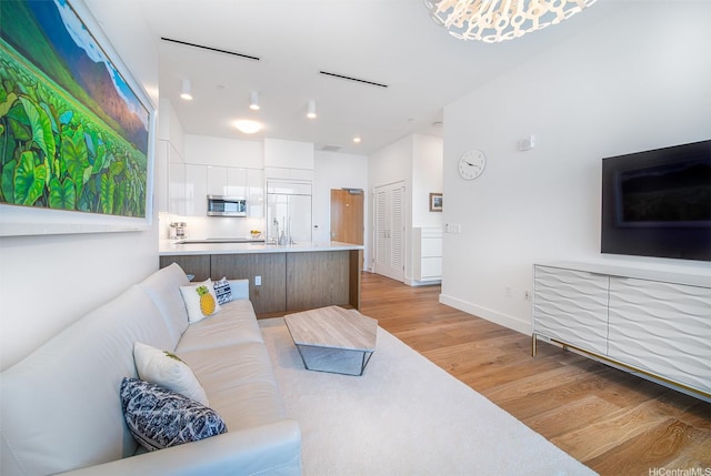 living room featuring recessed lighting, baseboards, and light wood-style floors