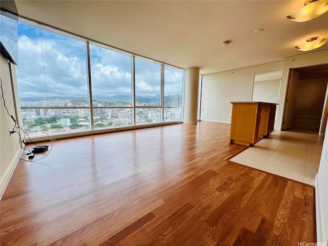 unfurnished living room featuring a wall of windows, wood finished floors, a wealth of natural light, and a mountain view