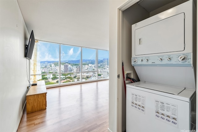laundry room with stacked washer / drying machine, wood finished floors, and laundry area