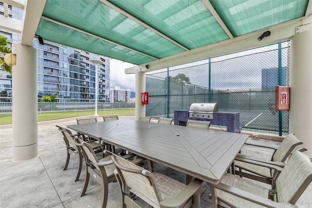view of patio with a city view, outdoor dining area, area for grilling, and fence