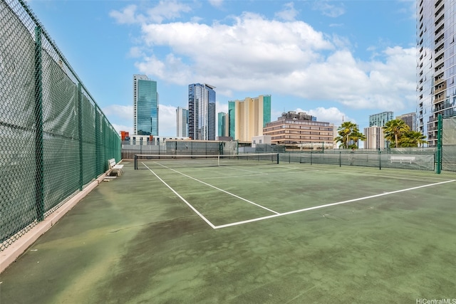 view of sport court featuring fence and a city view