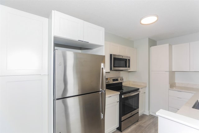 3161 Ala Ilima St Unit 403, Honolulu, HI 96818 - kitchen with light countertops, light wood-style floors, appliances with stainless steel finishes, and white cabinets