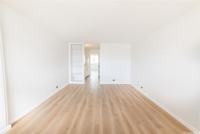 unfurnished room with baseboards and light wood-style flooring