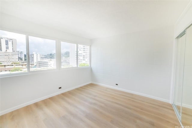 interior space featuring a view of city, baseboards, and light wood-type flooring