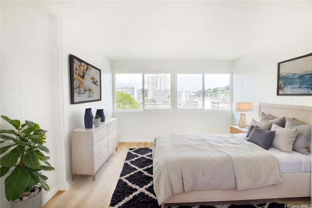 bedroom with light wood-style flooring, baseboards, and multiple windows