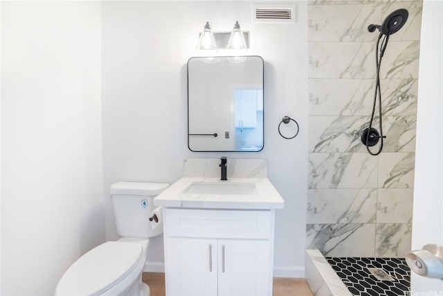 bathroom featuring tiled shower, visible vents, vanity, and toilet