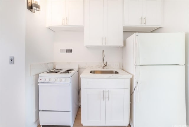 kitchen with white appliances, a sink, and white cabinetry
