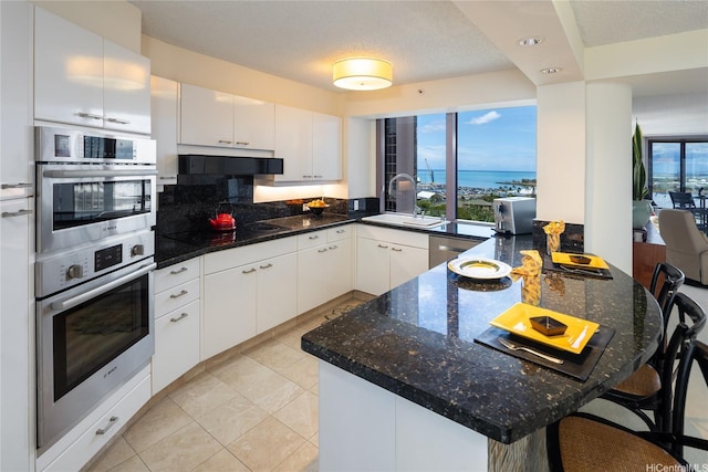425 S St Unit 1401, Honolulu, HI 96813 - kitchen with a peninsula, under cabinet range hood, a sink, appliances with stainless steel finishes, and white cabinets