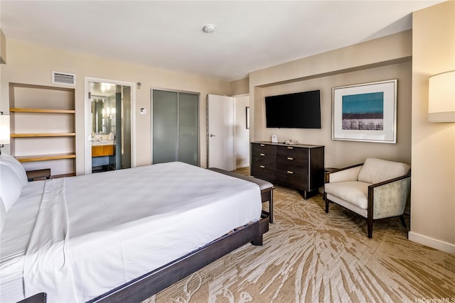 carpeted bedroom with baseboards, ensuite bath, and a closet