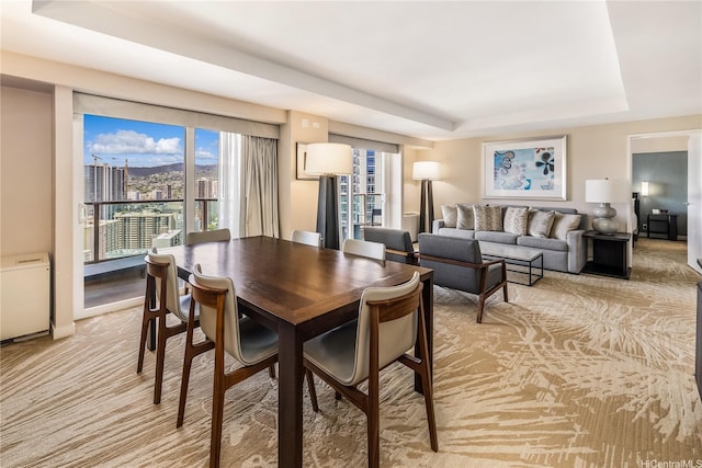 dining area featuring a tray ceiling and light carpet
