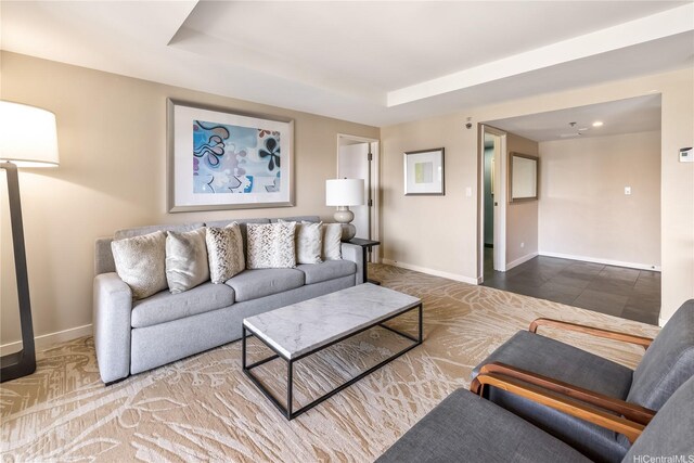 living room with baseboards and a raised ceiling