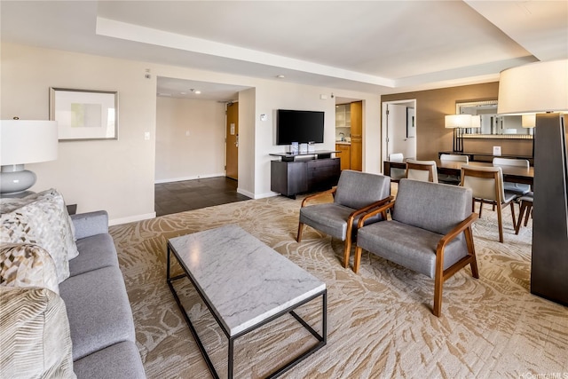living room featuring a raised ceiling and baseboards