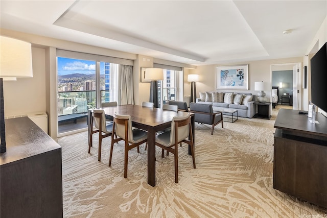 dining room with a raised ceiling and light carpet