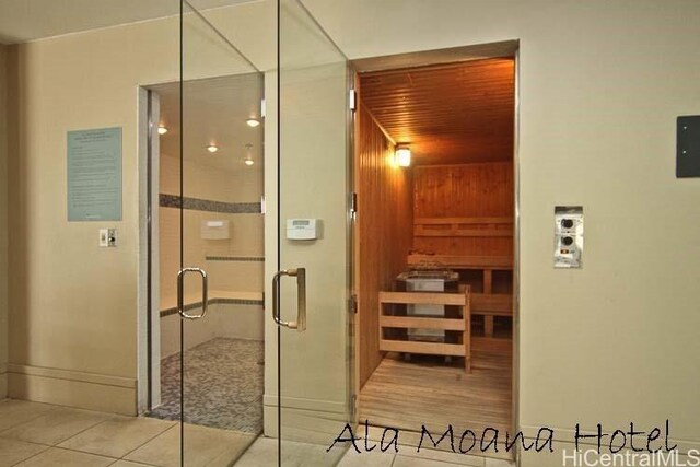 relaxing sauna with tile patterned flooring and baseboards