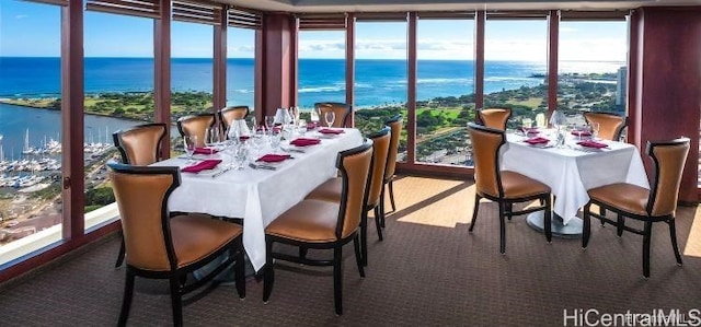 dining space with a water view, expansive windows, and carpet