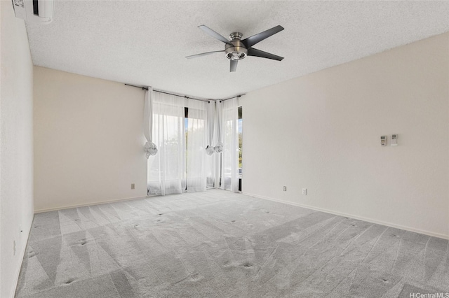 carpeted empty room featuring a ceiling fan, baseboards, and a textured ceiling