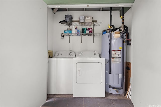 laundry room featuring washer and dryer, dark tile patterned floors, laundry area, and water heater