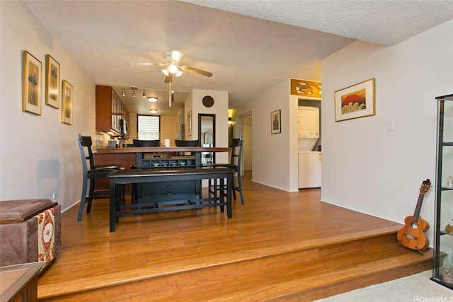 521 Hahaione St Unit 2-6J, Honolulu, HI 96825 - dining area featuring a textured ceiling, ceiling fan, stacked washer and dryer, and wood finished floors