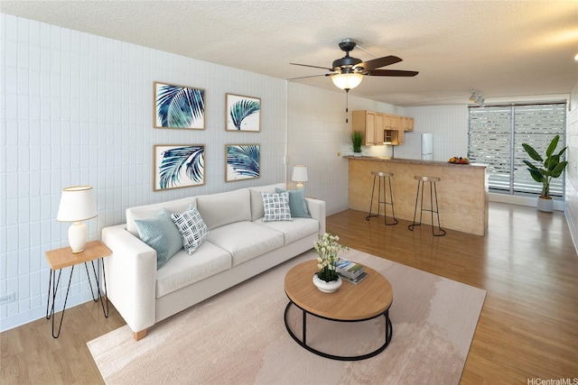1524 Pensacola St Unit 217, Honolulu, HI 96822 - living room featuring light wood-style flooring, a textured ceiling, a ceiling fan, and tile walls