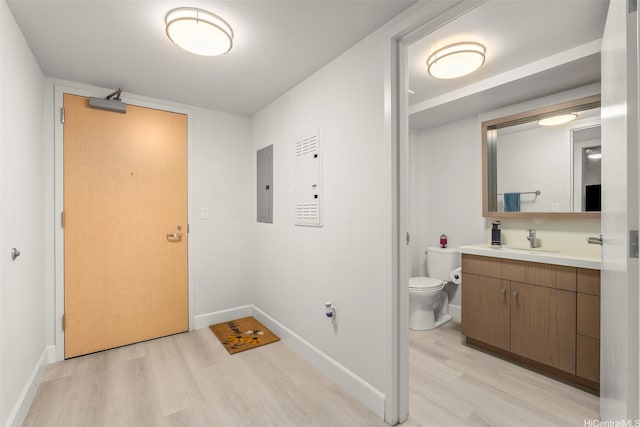 interior space featuring light wood finished floors, electric panel, baseboards, and a sink