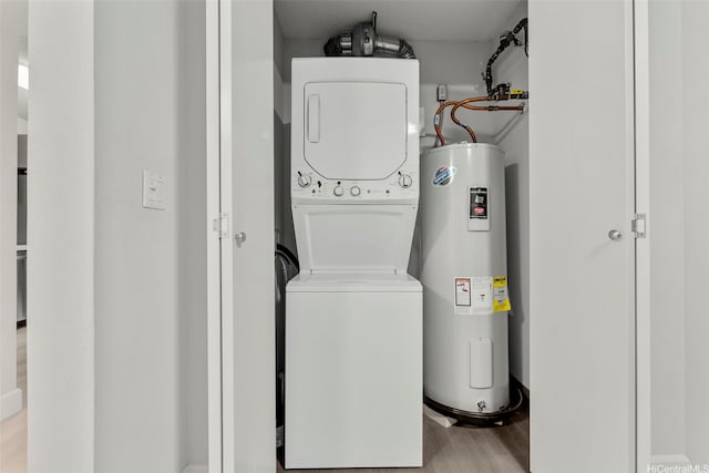 clothes washing area with wood finished floors, water heater, stacked washer / dryer, and laundry area
