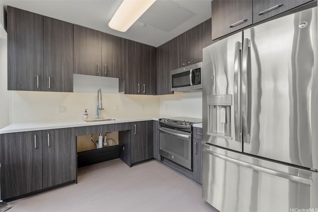 kitchen featuring appliances with stainless steel finishes, dark brown cabinets, a sink, and light countertops