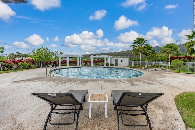 pool with a pergola, fence, and a patio area