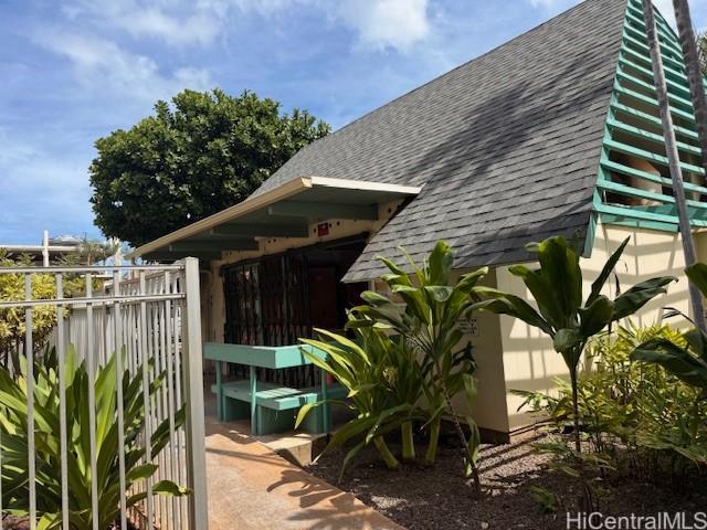 view of home's exterior with roof with shingles and fence