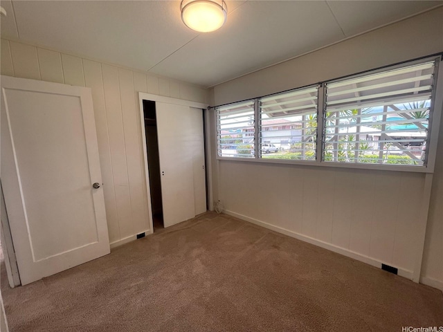 unfurnished bedroom with a closet, light carpet, and baseboards