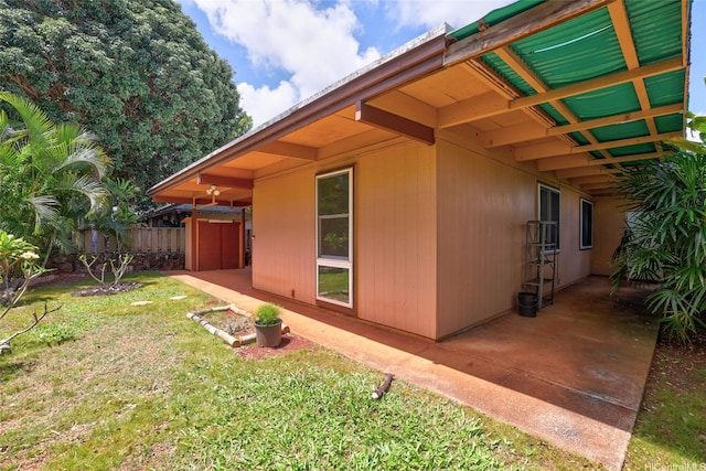 view of side of home featuring a lawn, fence, and a patio area