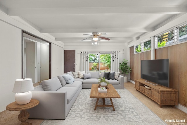 living area with a ceiling fan, wooden walls, and beam ceiling