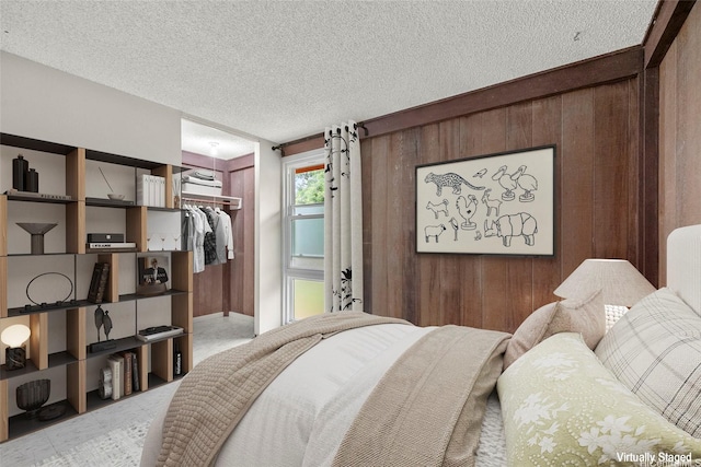 bedroom featuring a textured ceiling, a closet, wood walls, and a spacious closet
