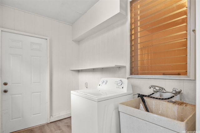 clothes washing area featuring light wood-type flooring, a sink, laundry area, and washer / clothes dryer