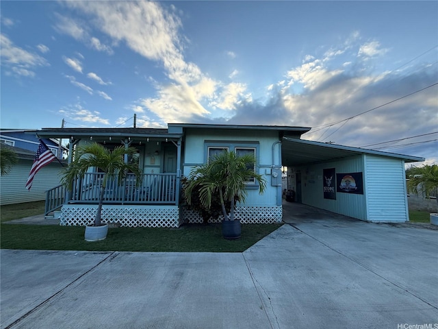 view of front of property with concrete driveway, a carport, and covered porch