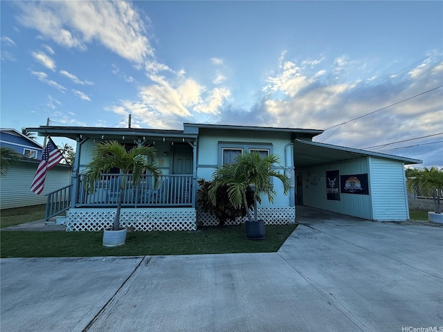 view of front facade with a porch, a carport, and concrete driveway