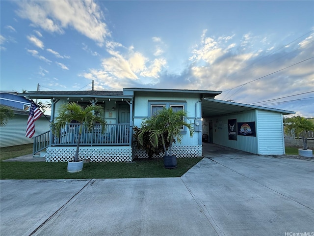 view of front of house with a porch, concrete driveway, and an attached carport
