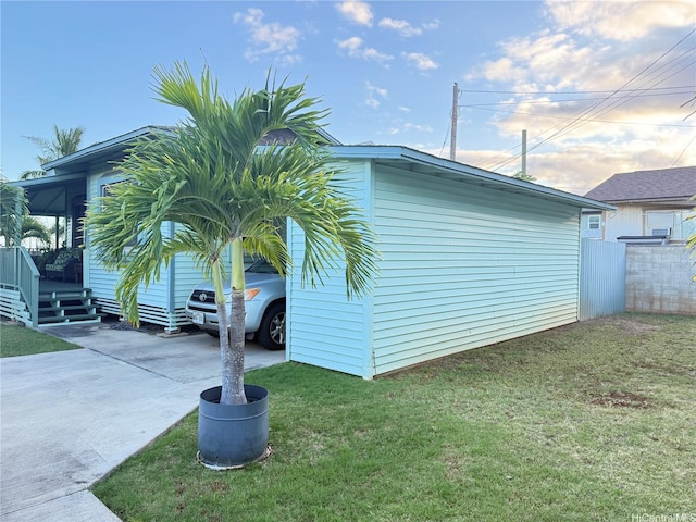 view of side of property featuring a lawn and concrete driveway