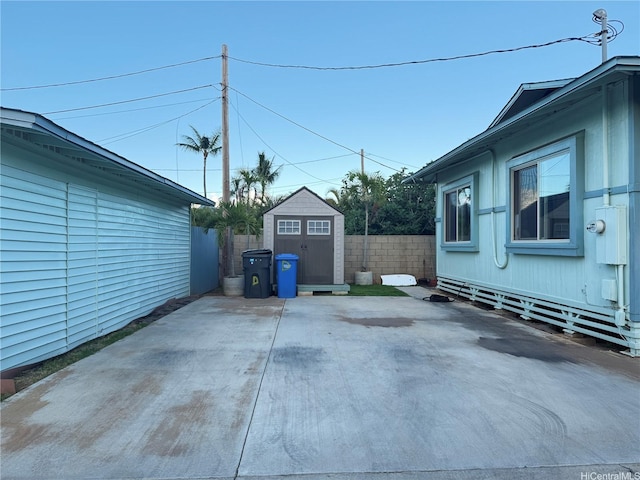 exterior space featuring a shed, fence, an outbuilding, and a patio