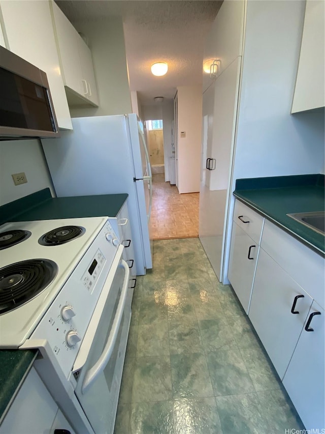 1670 Kalakaua Ave Unit 401, Honolulu, HI 96826 - kitchen featuring electric stove, stainless steel microwave, white cabinets, and dark countertops