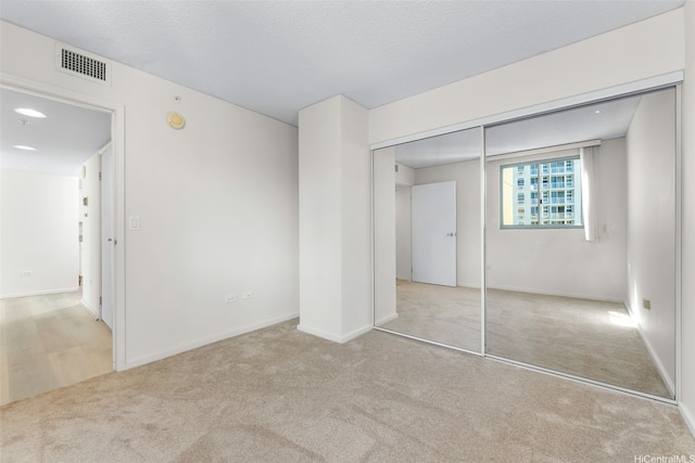 unfurnished bedroom with baseboards, visible vents, carpet, and a closet
