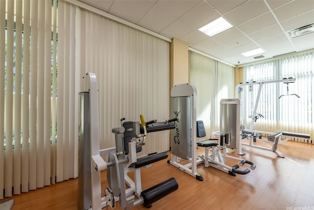 workout area with wood finished floors, visible vents, and a drop ceiling