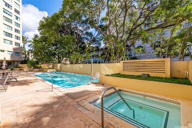 pool featuring fence, a hot tub, and a patio