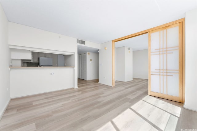 unfurnished living room featuring wood finished floors and visible vents